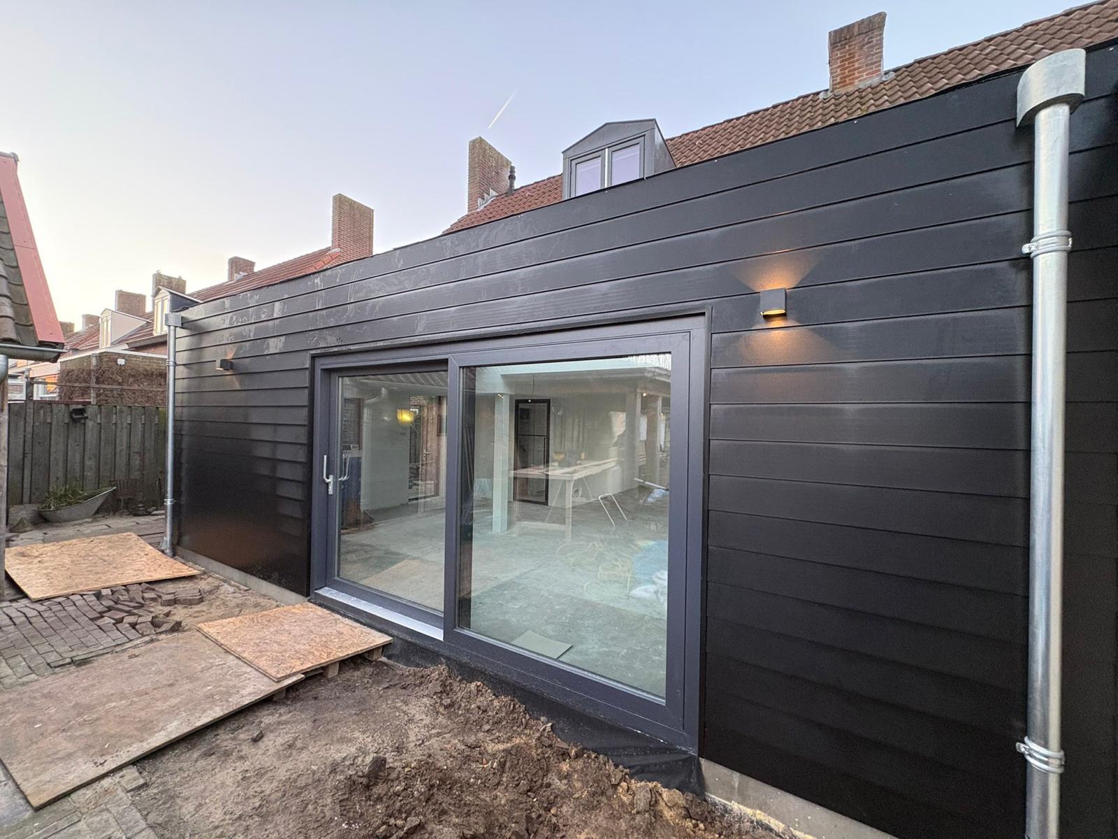 Uitbouw woonkamer - afgeronde aanbouw met zwarte gevelbekleding